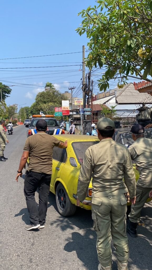 Petugas Satpol PP Jembrana memindahkan mobil rusak dari trotoar Jalan Udayana