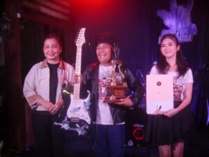 Pemenang Ireng Kopi Music Battle memegang gitar dan piala Juara 1