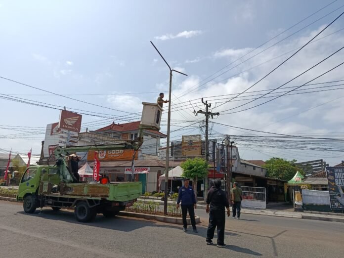 Petugas merapikan kabel fiber optik yang menjuntai di Jalan Ngurah Rai