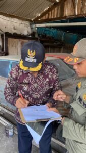 Pejabat dan petugas Satpol PP menandatangani berita acara penertiban mobil rusak di Jalan Udayana