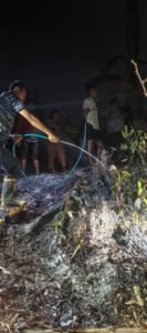 Warga menyemprotkan air ke lahan kebun yang terbakar di Warnasari Kelod pada malam hari